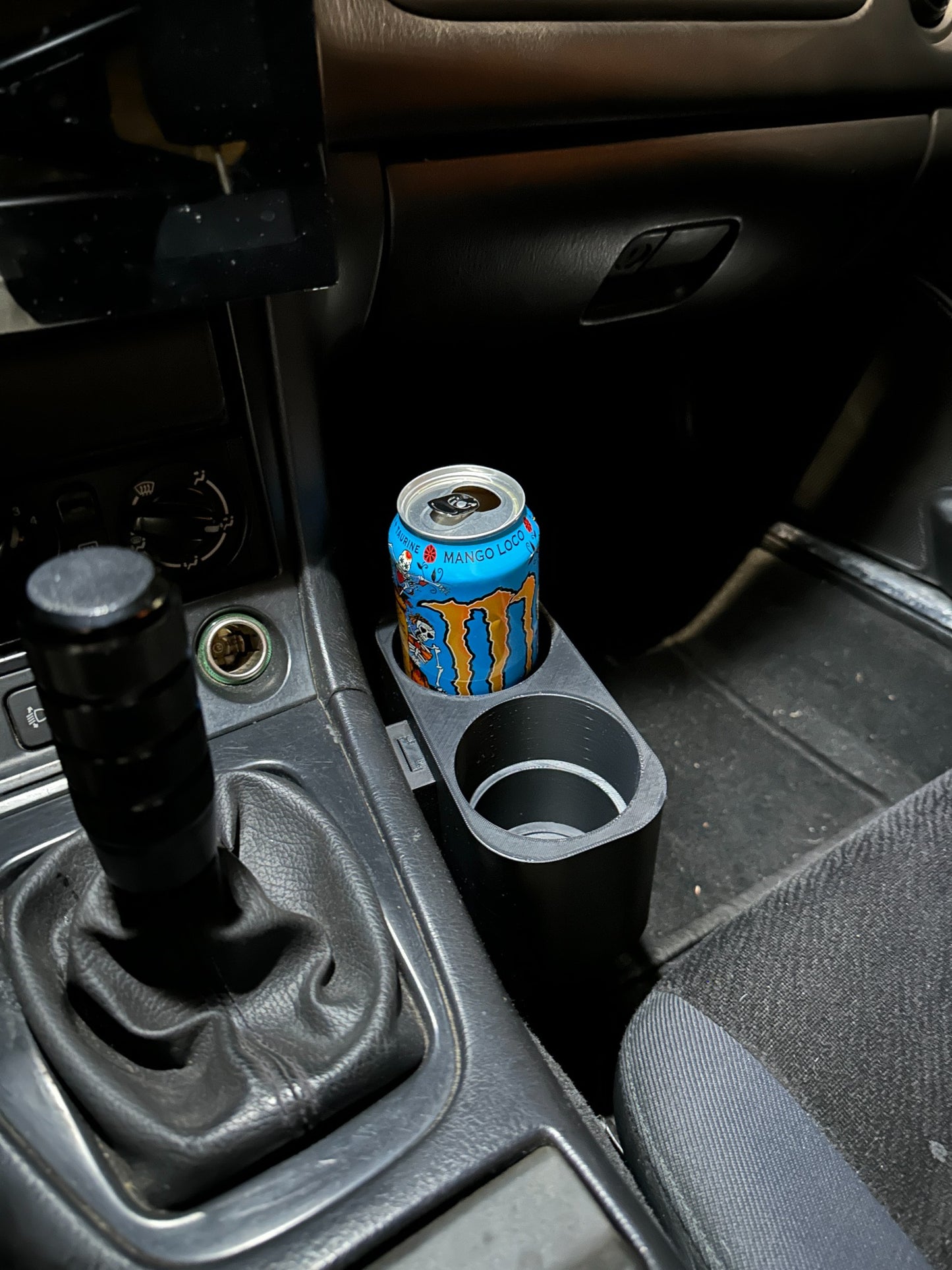 Een Monster Energy-blikje geplaatst in een 3D-geprinte bekerhouder in een Mazda MX-5 NA/NB.