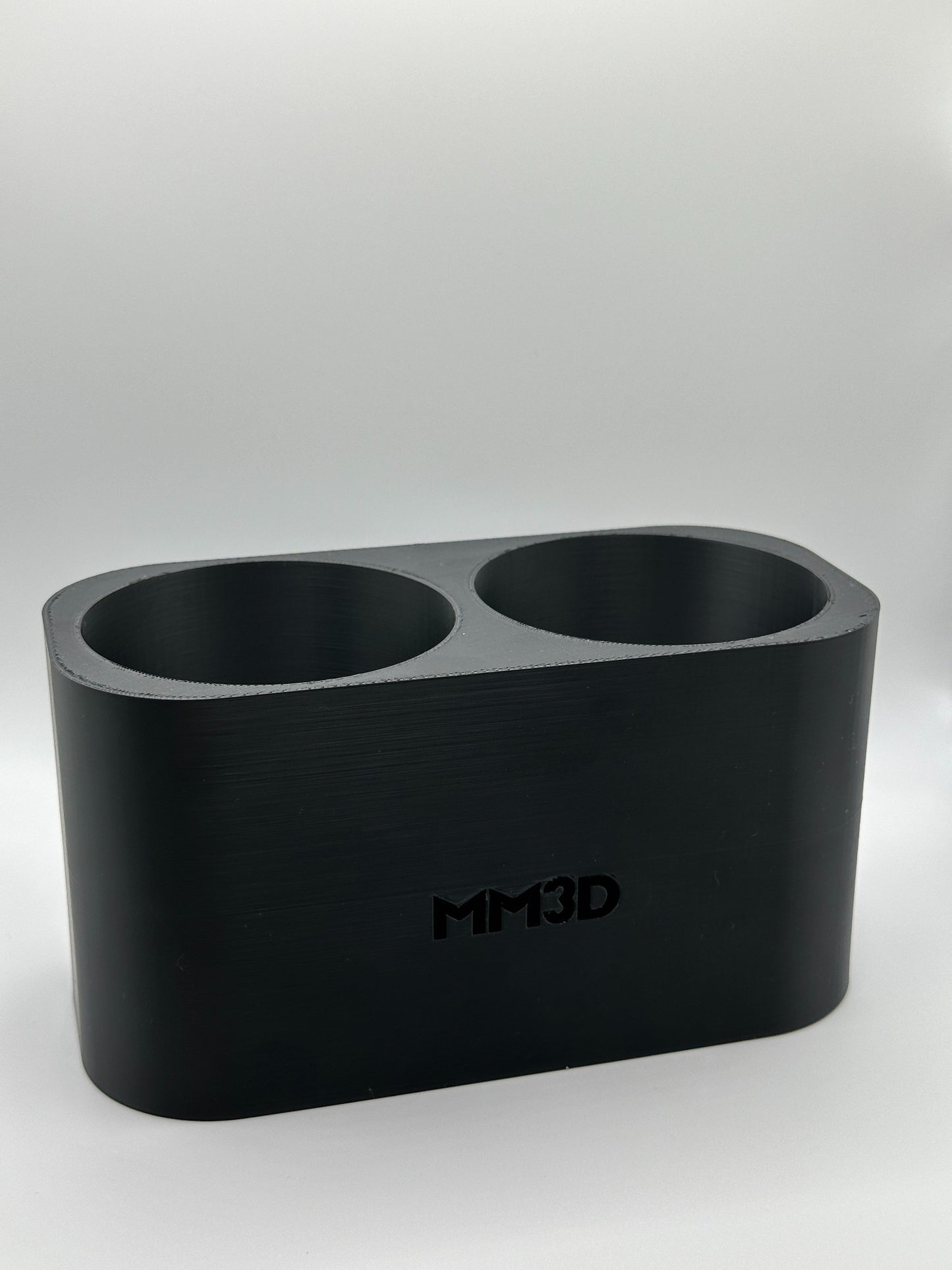 Close-up van een op maat gemaakte 3D-geprinte bekerhouder met het MM3D-logo in het ontwerp.
